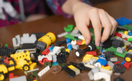 male hands search suitable toy block on wooden table b